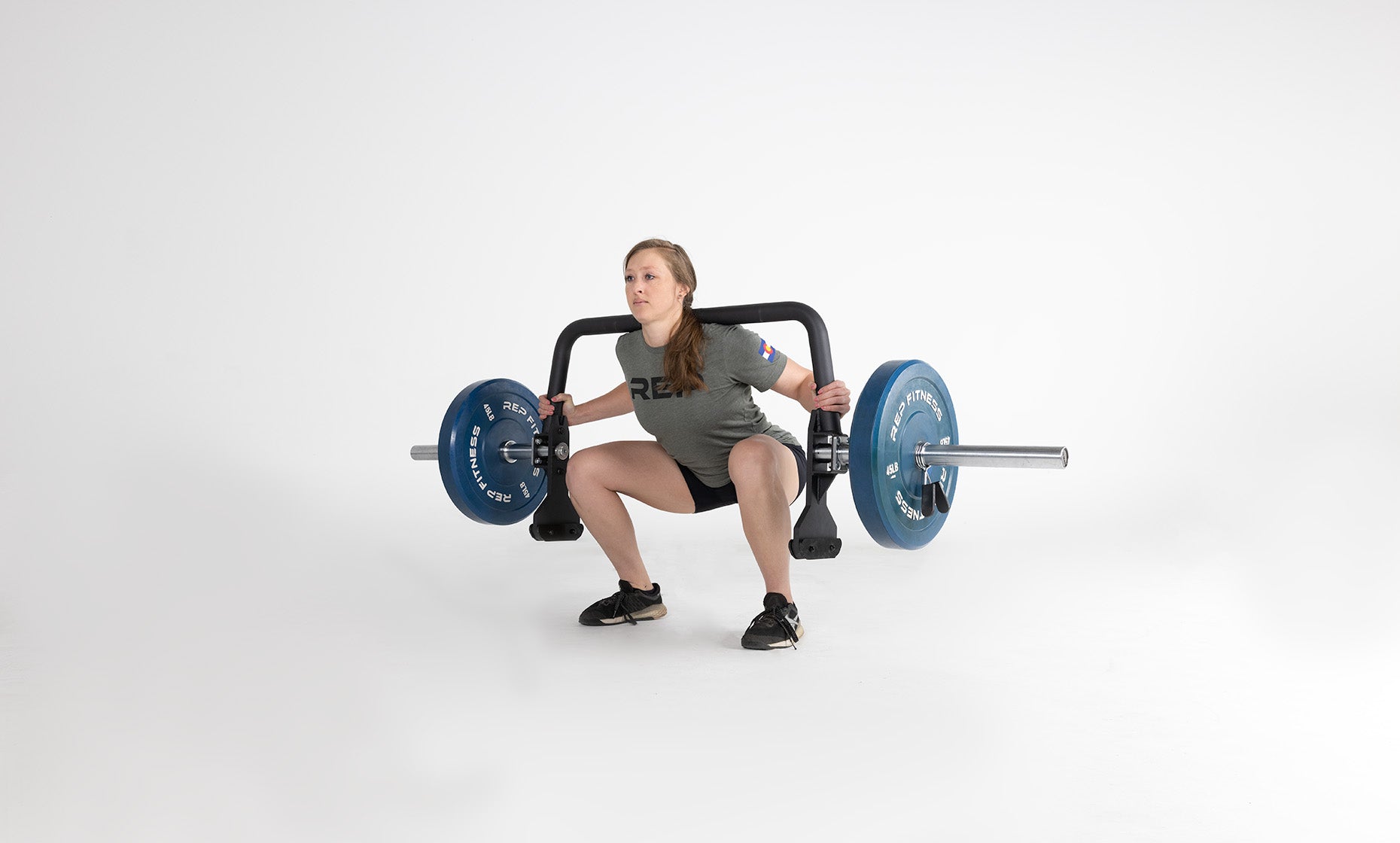 Lifter in the bottom of a squat with the Open Trap Bar racked on her back without handles attached.
